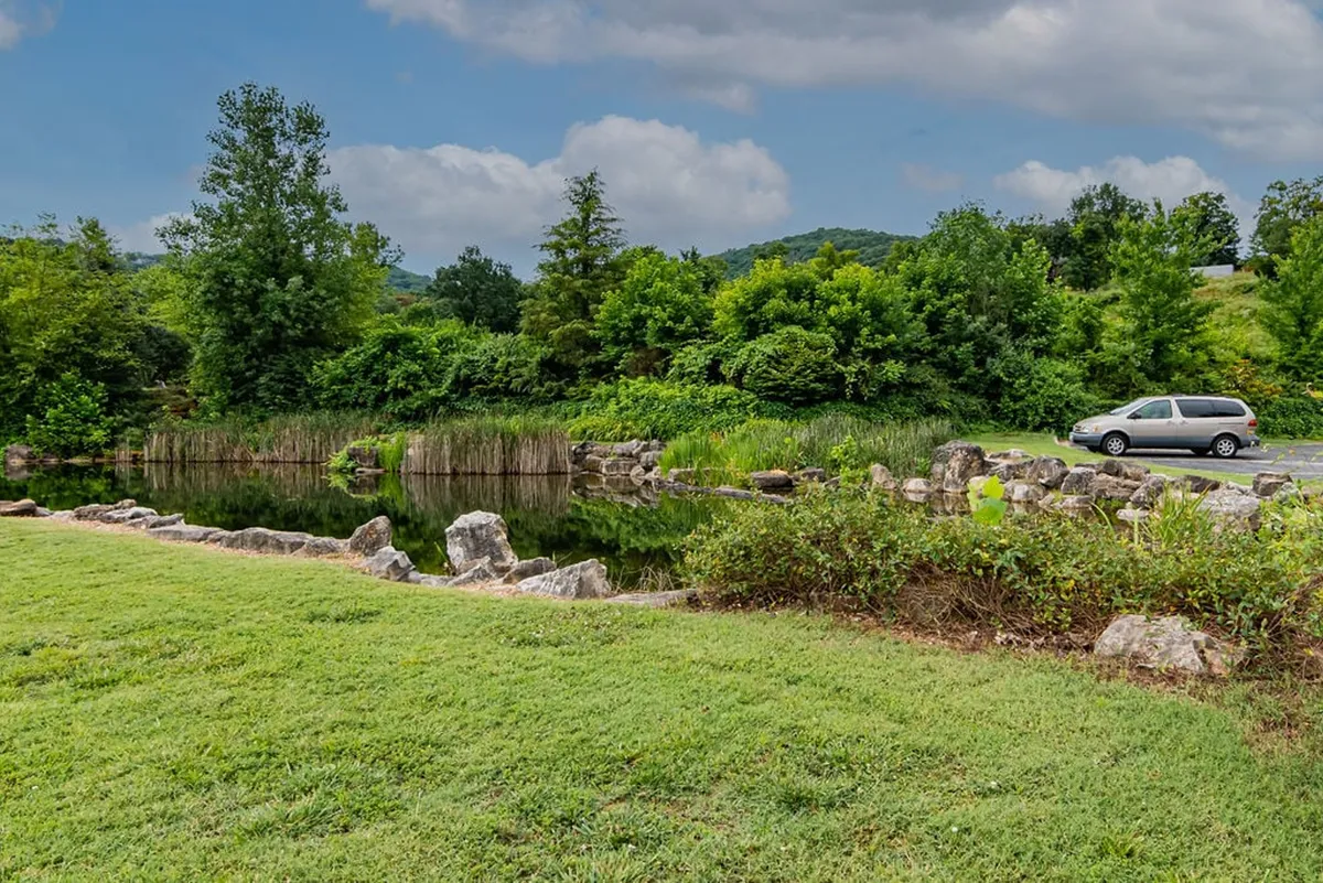 A calm body of water bordered by rock formations and vibrant greenery, with distant hills completing the landscape. The tranquil atmosphere makes it ideal for kayaking, wildlife watching, and enjoying sunset vistas.