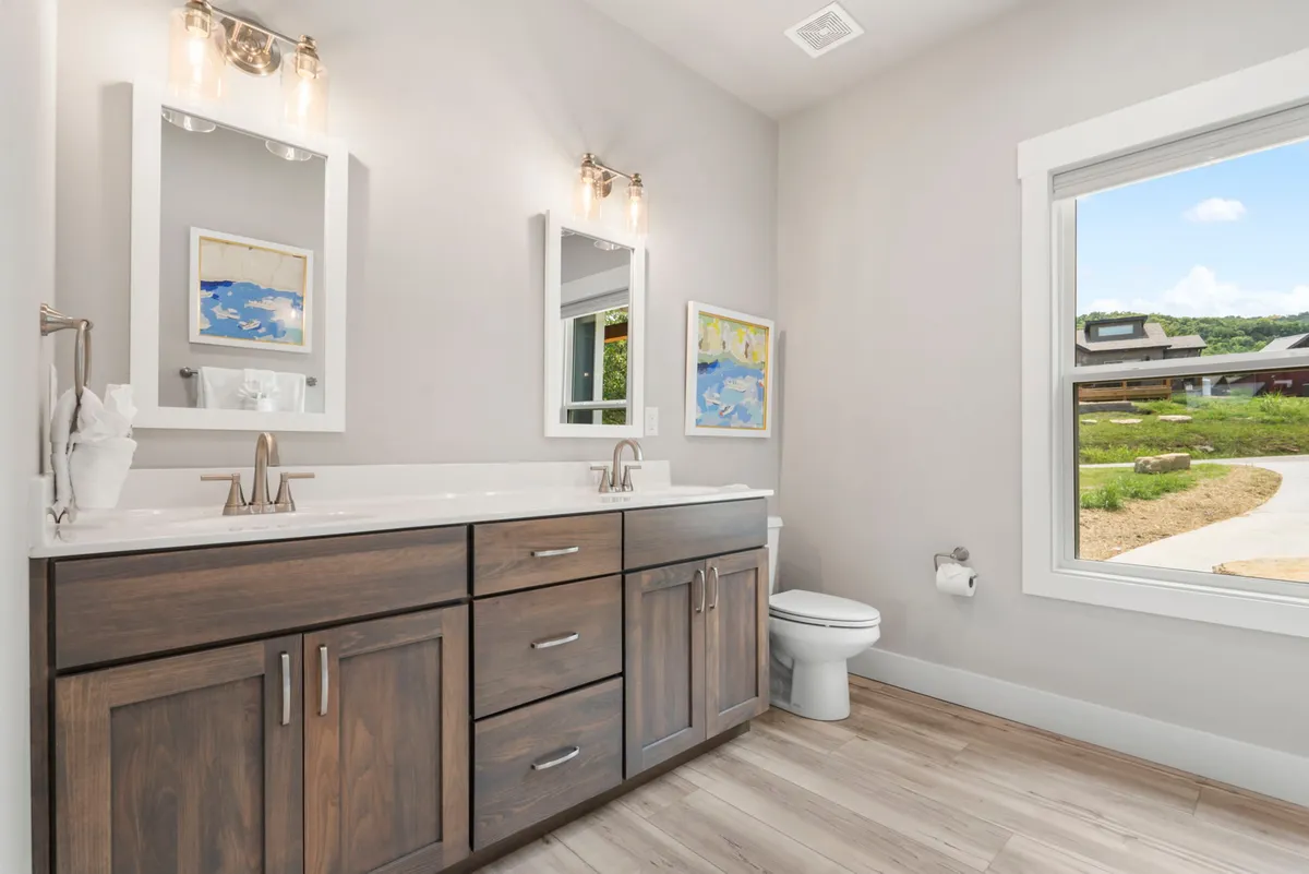 A spa-inspired bathroom with dual sinks, elegant mirrors, artwork, and a window. The space feels fresh and serene, ideal for morning routines or unwinding after a day of adventure.