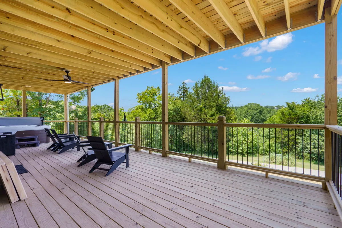 A tranquil exterior deck scene featuring a private hot tub, wooden decking, comfortable seating, and surrounding greenery. The serene setup suggests a perfect place to unwind after a busy day exploring nearby attractions, with views of nature and sky.