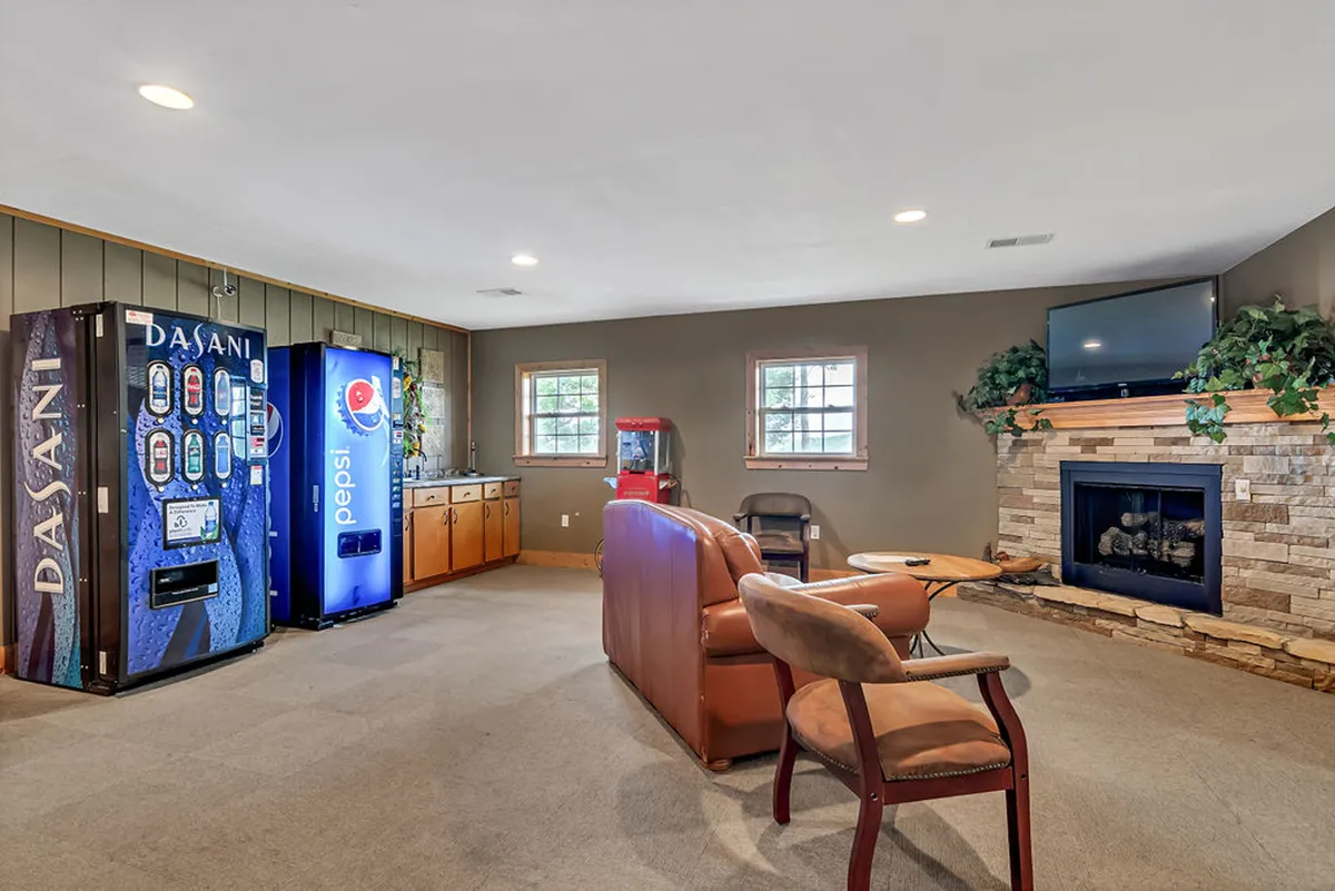 An inviting lounge area featuring comfortable seating, a warm fireplace, vending machines, and a television. The casual, communal vibe is perfect for socializing, game nights, or cozy relaxation during rainy days or evenings.