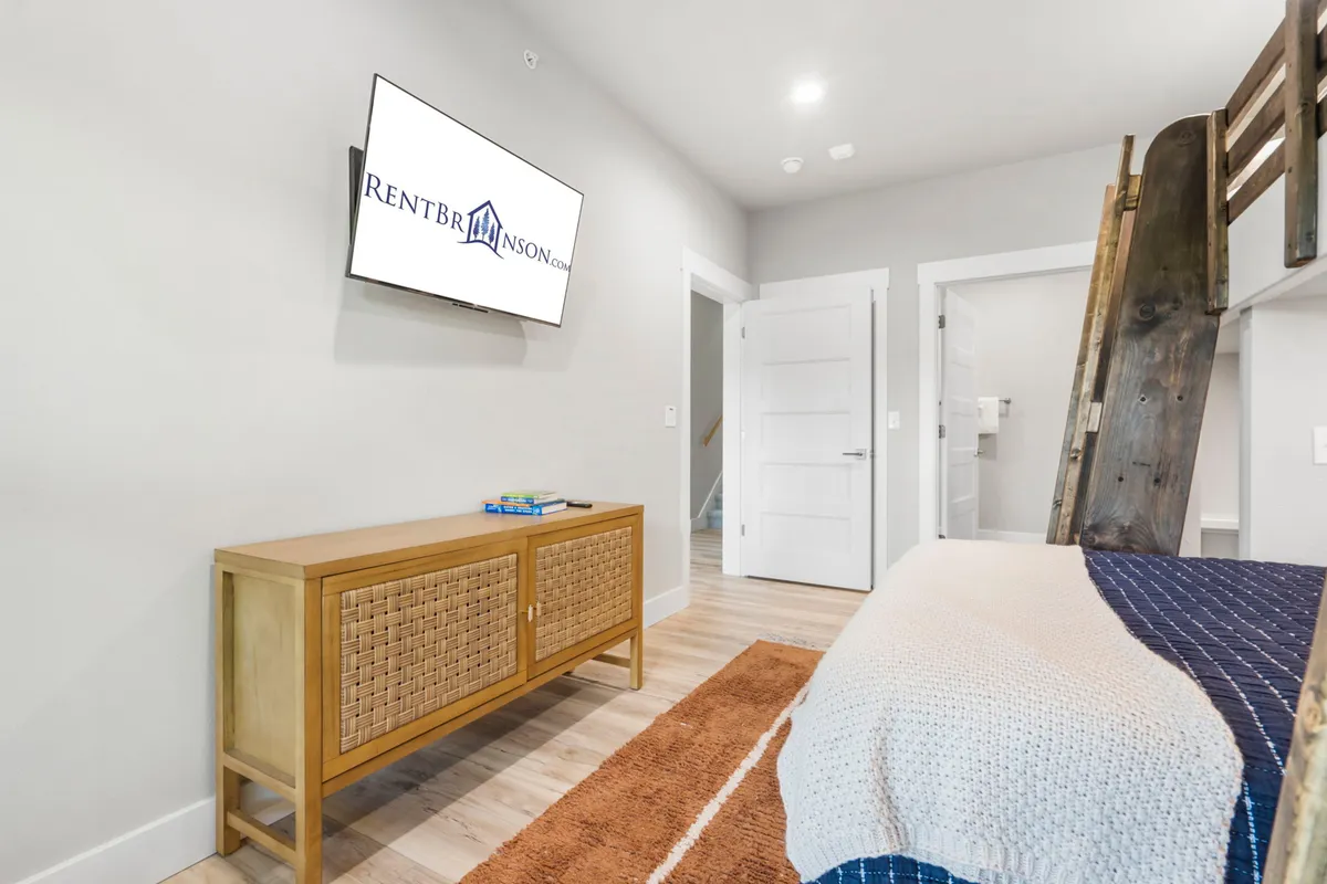 A cozy nook with a bunk bed, wall-mounted TV, and wooden storage unit. The space is inviting and designed for relaxation or late-night movies, ideal for children or teens seeking their own spot to unwind.